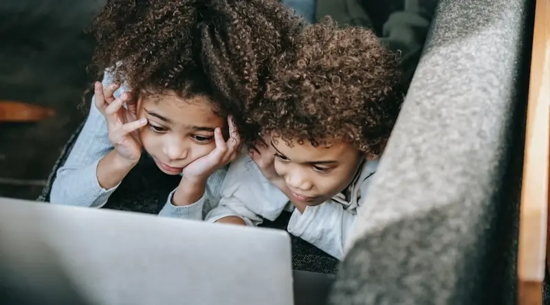 Two kids sitting in front of a screen