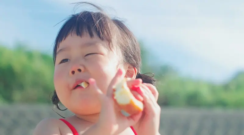 Girl eating an apple at the beach
