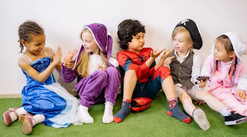 Kids playing on the ground dressed as Disney characters and supper heroes