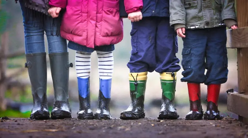 children in rubber boots staying on a muddy road