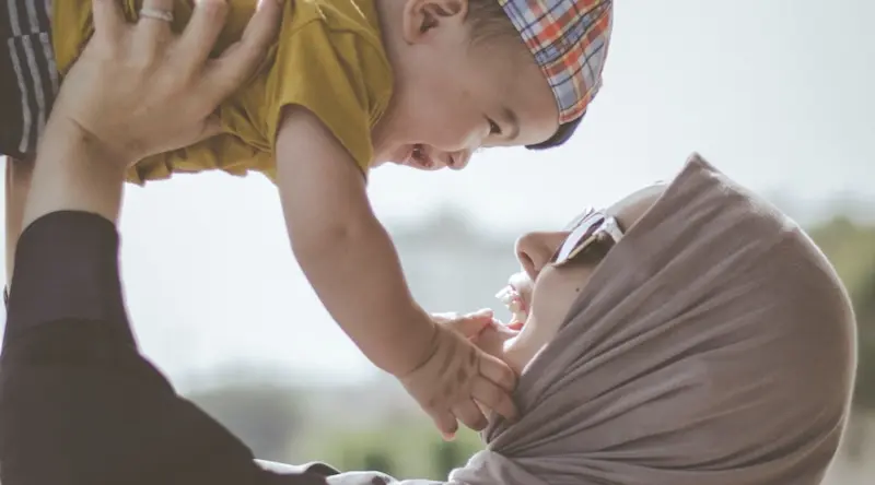 Mother holding giggling toddler in the air