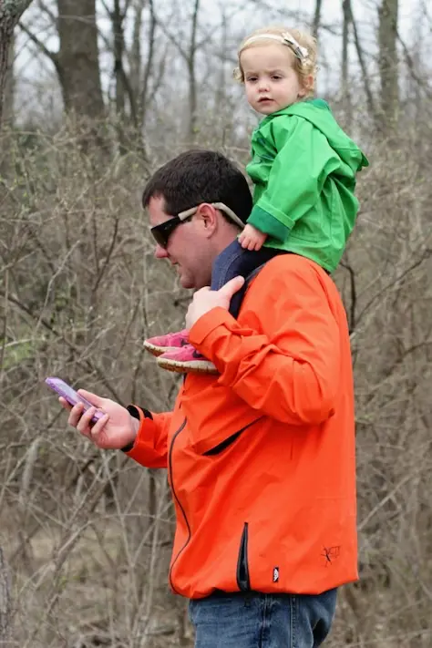 tall man with a child on his shoulders playing GeoCaching