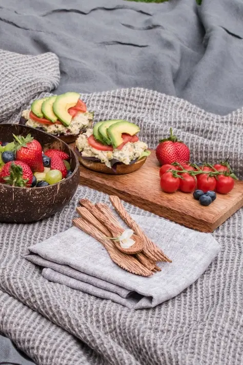 picnic blanket with sandwiches and fruits