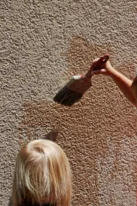 child painting wall with water