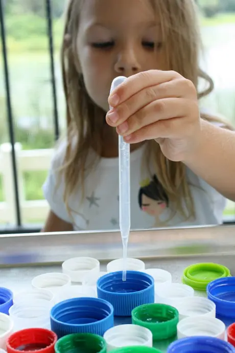 chld using pipette to put water into bottle caps