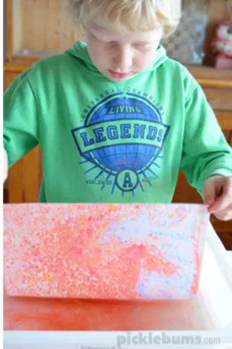 child holding chalk covered paper over water
