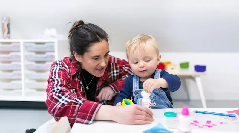 Nursery staff helping blonde child
