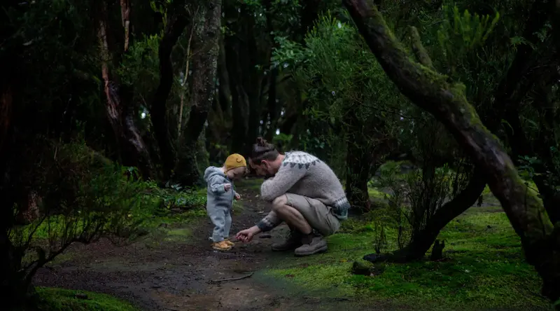 father playing with his toddler in a deep green forest