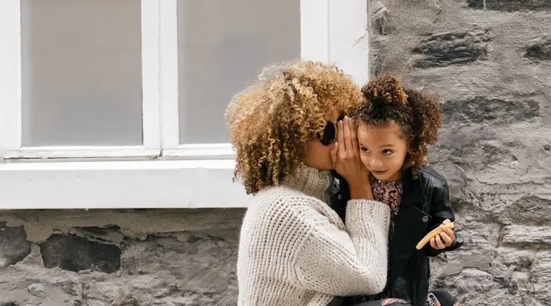 mother whispers in daughter's ear