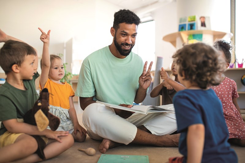 teacher sits teaching nursery children