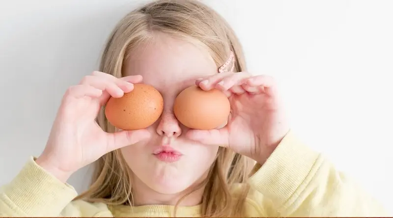 Girl holding eggs in front of her eyes and making funny faces