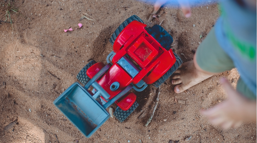 toddler standing over red digger truck