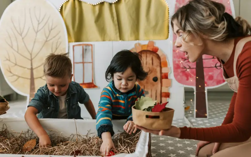 preschool teacher playing with two children  