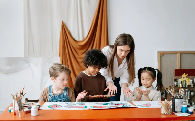 early educator teaching three kids in arts and crafts