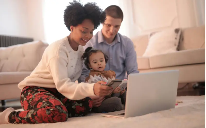 mom checking phone and computer for updates of their toddler on their communication app
