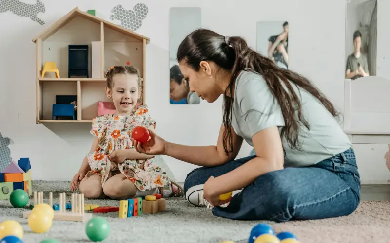 preschool teacher playing on the floor with child