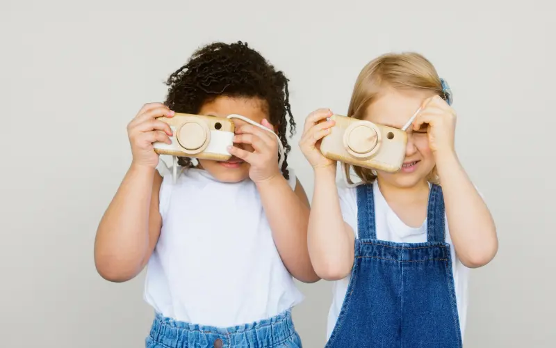 two young girls playing with wooden cameras