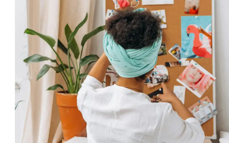 a woman making a collage of her favorite things on a bulletin board