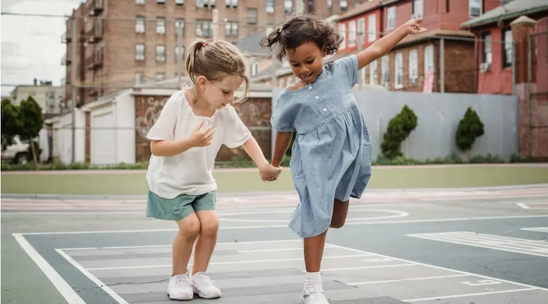 two young girls playing hopscotch outside school