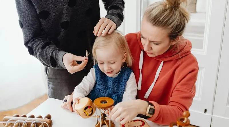 two parents playing with their young daughter
