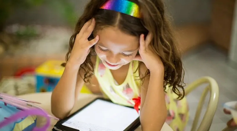 a young girl reading something on her tablet
