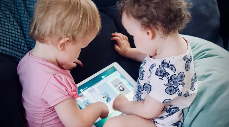 two babies playing a game on a tablet