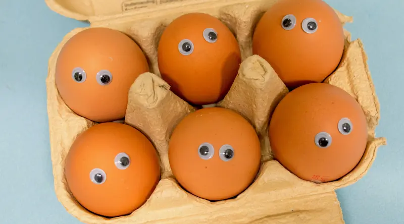 box with 6 eggs all with googly eyes stuck on them