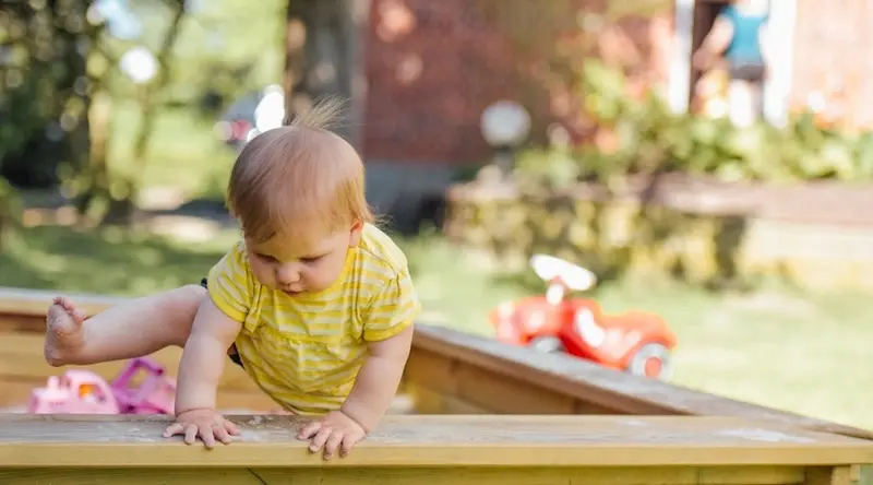 child climbing out of the sandbox