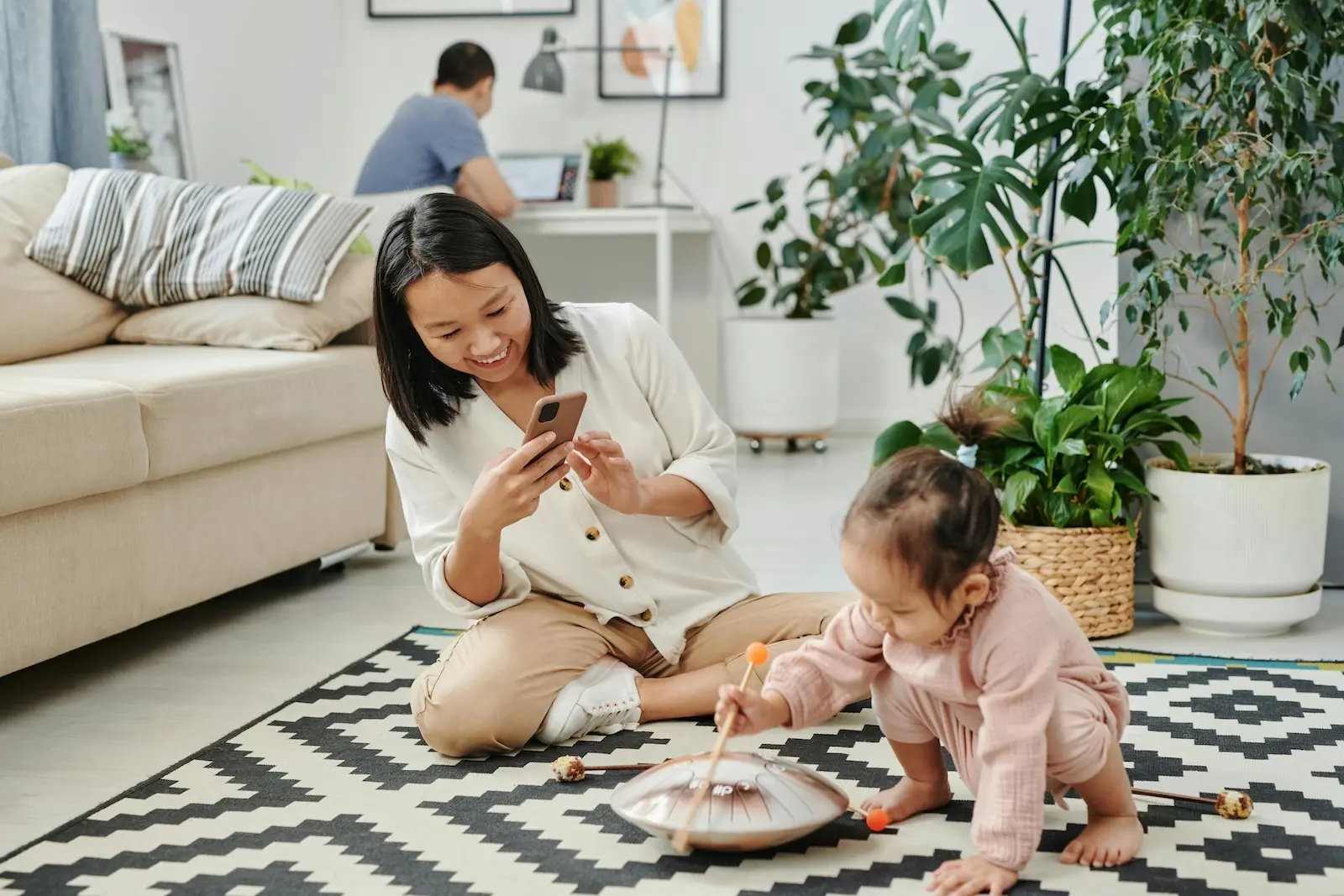 A mother taking a photo of her young daughter playing to share with family