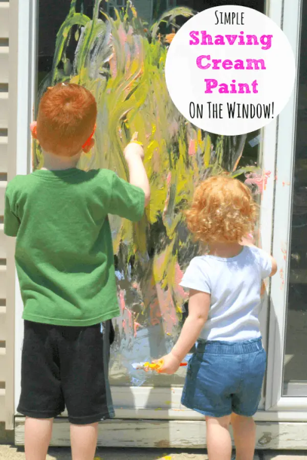 two kids playing with shaving cream on the window