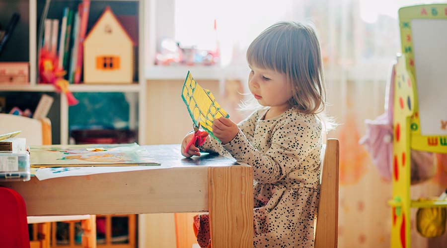 A child cutting shapes at nursery during play time