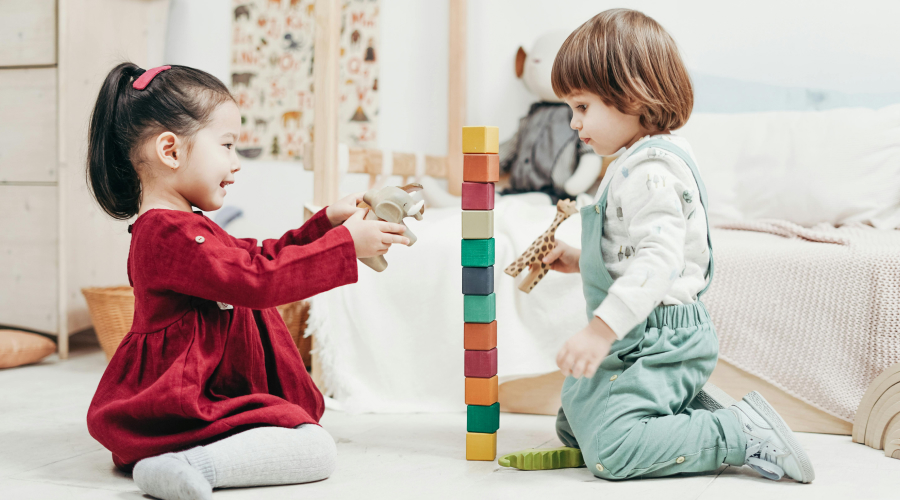 two young kids uilding a tower with colorful wooden blocks
