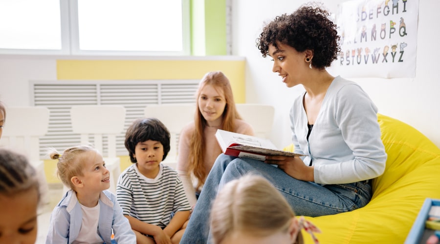 woman reading from a book to a group of sitting children