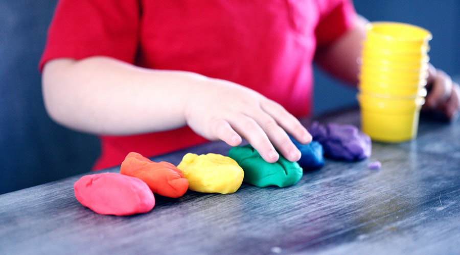 toddler's hands playing with rainbow playdough