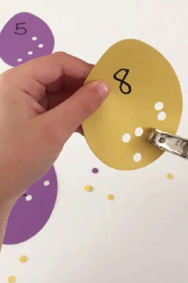 A hand holding a colorful paper with a drawn number 8