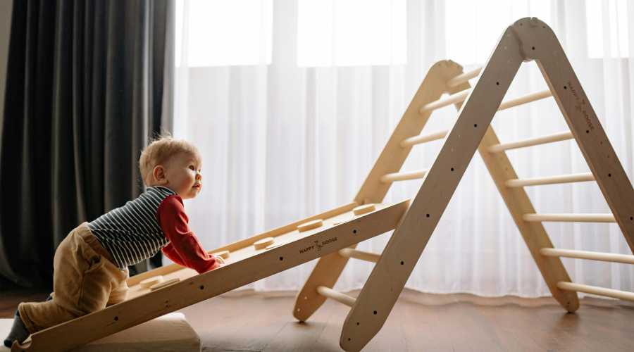 baby crawling up wooden play structure
