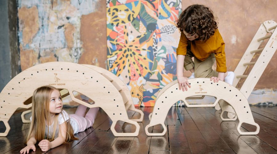 preschool boy and girl climbing on wooden toys