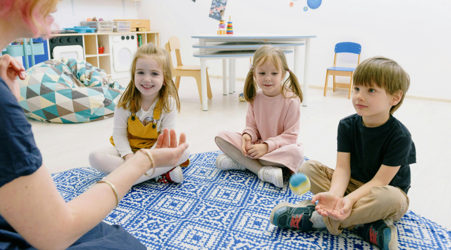 preschoolers in a circle on the floor with their teacher