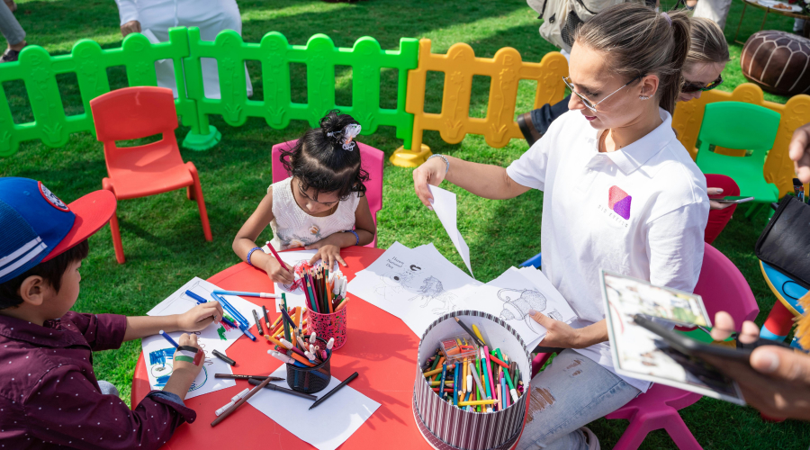 preschool children and teacher sitting outside coloring