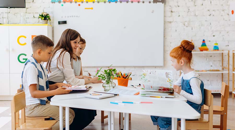Four young children sit and draw at a table