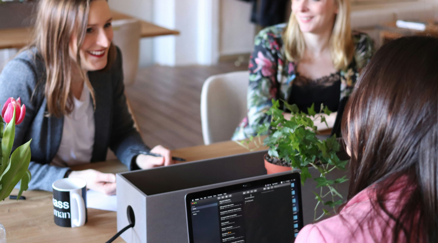 three women looking at laptops at a business meeting