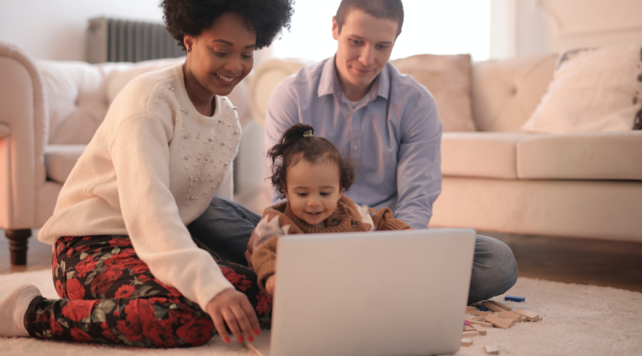 parents and toddler looking at laptop together