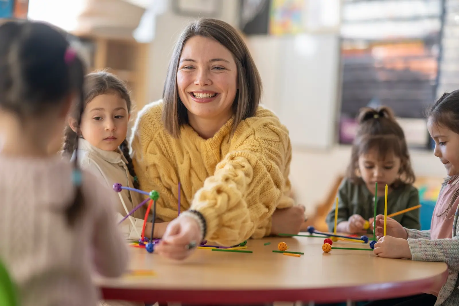teacher playing and smiling with preschoolers