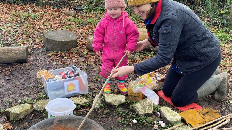 An adult (Heather Thomas) and a child setting up a campfire at Cywion Bach's forest school.