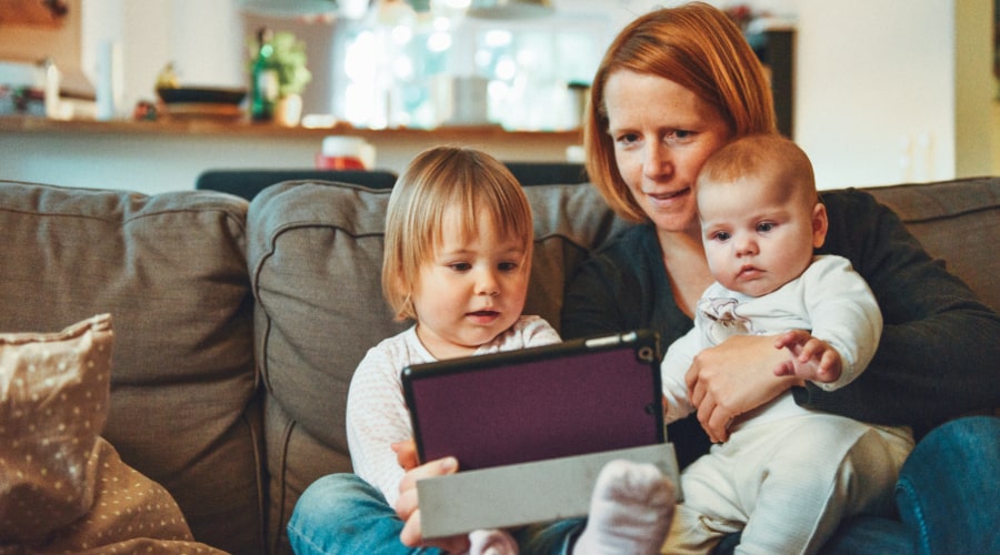 A woman with two babies sitting on a sofa