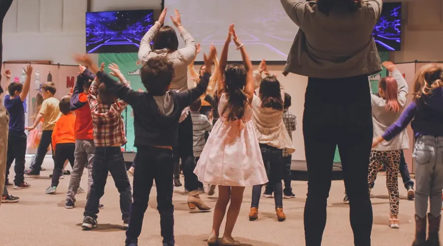 Early years children dance and sing together
