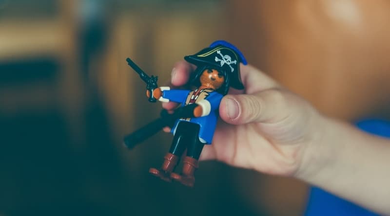 Hand holding a small pirate figure with a gun in hand
