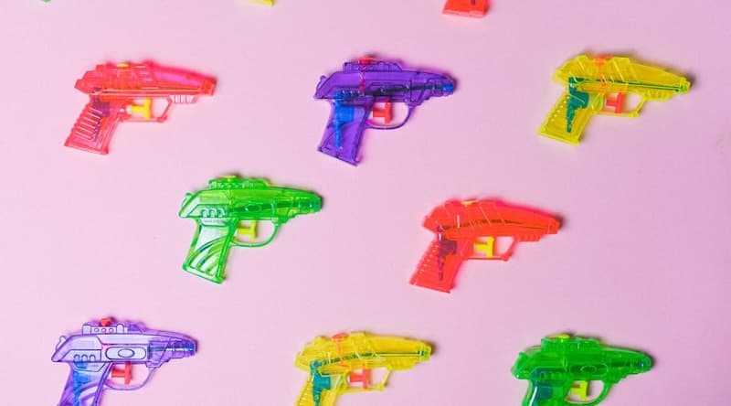 Plastic water guns on pink background