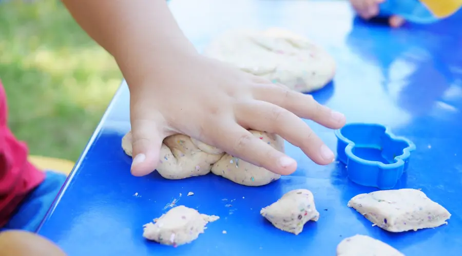 A child's hand pushed down on some playdough