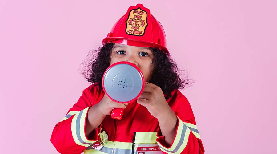 A photo of a little girl wearing a fire fighter uniform, speaking into a megaphone